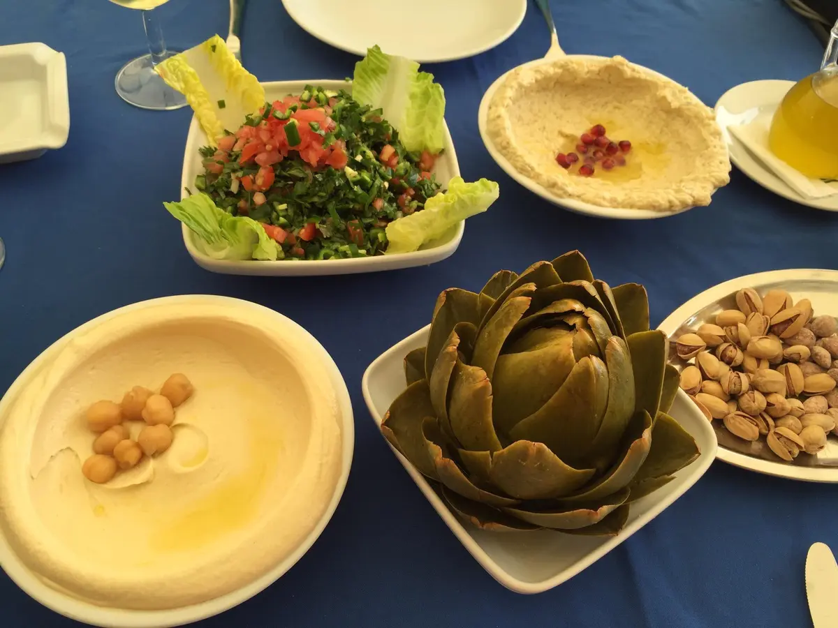 11 Best Lebanon Restaurants: A Food Critic's Guide 7 A table covered in Lebanese mezze dishes at Mounir restaurant, with the Broumana mountain and sea view in the background.